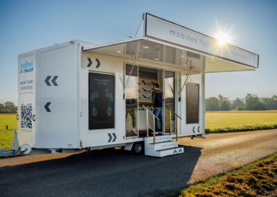 Fit Trailer ohne Van geoeffnet aus der Schraege mit Menschen Querformat